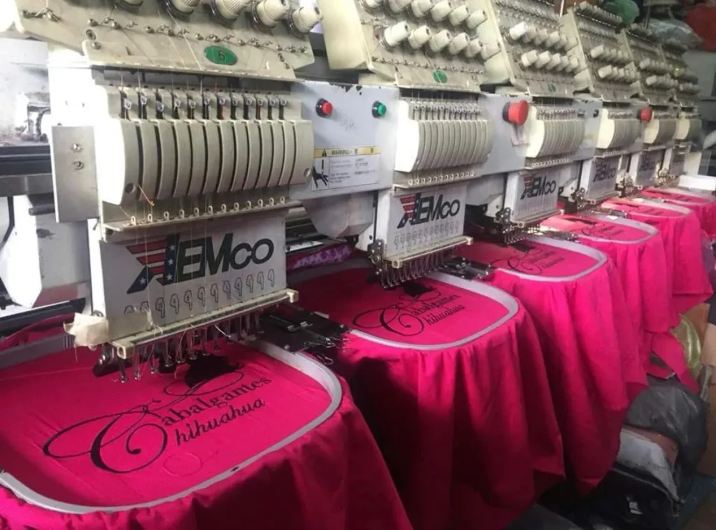 vista cercana de como la maquina bordadora de 8 cabezas esta bordando simultáneamente las camisas y blusas vaqueras para cabalgantes chihuahua
